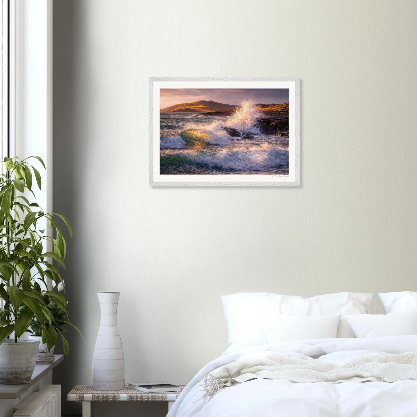 Framed artwork of a coastal scene above a bed in a bedroom.