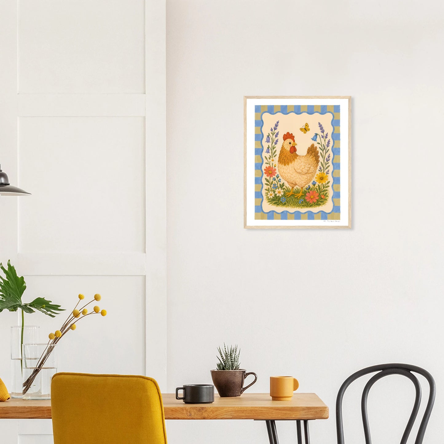 Framed artwork of a rooster on a wall above a table with chairs.