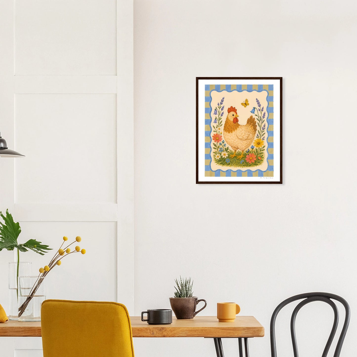 Framed artwork of a rooster on a wall above a table with chairs.