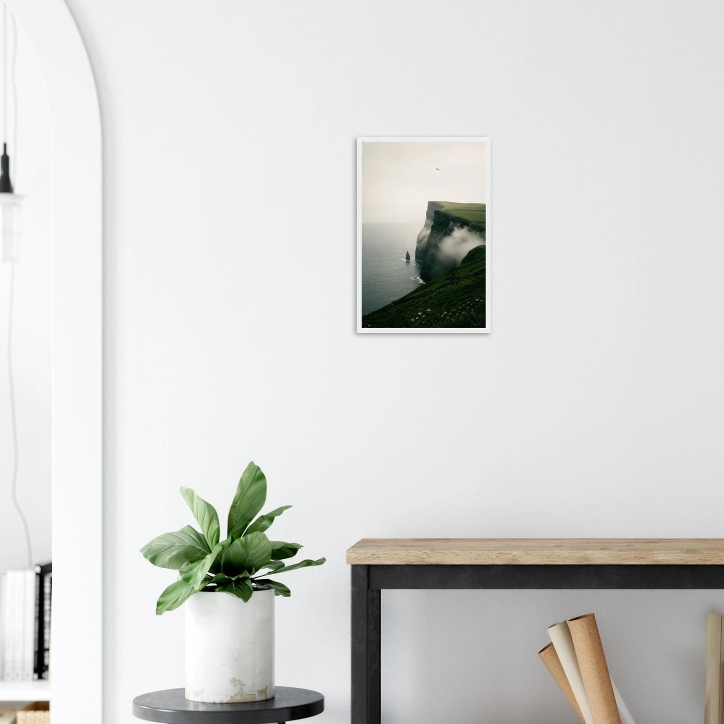 Modern interior with a plant, table, and framed picture on a white wall