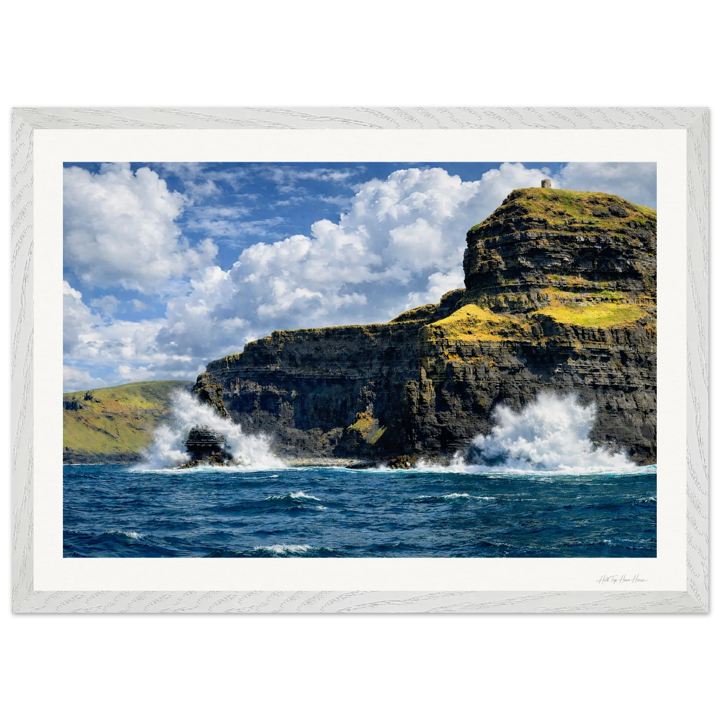 Rugged cliffs with ocean waves crashing against them under a blue sky with clouds.