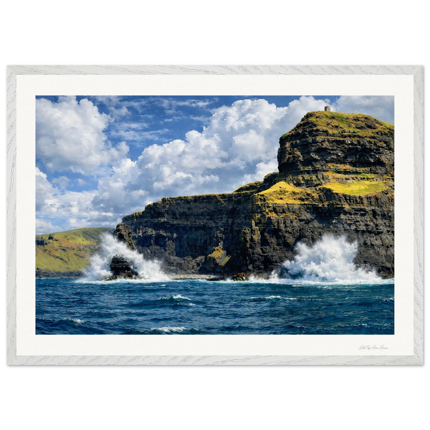 Cliffs with ocean waves crashing against them under a blue sky with clouds.