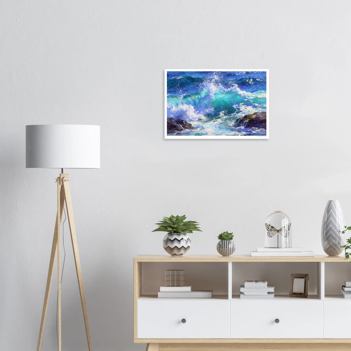 Framed artwork of a wave painting on a wall above a wooden shelf with decorative items.