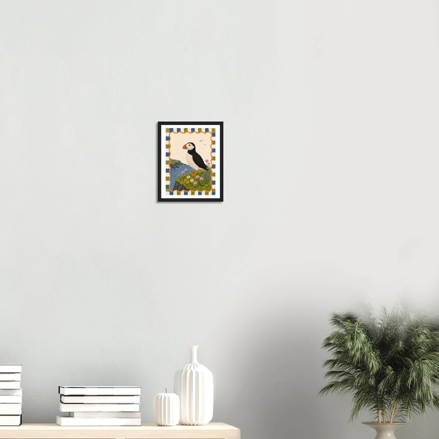 Framed artwork of a mountain landscape with a sunset on a white wall.