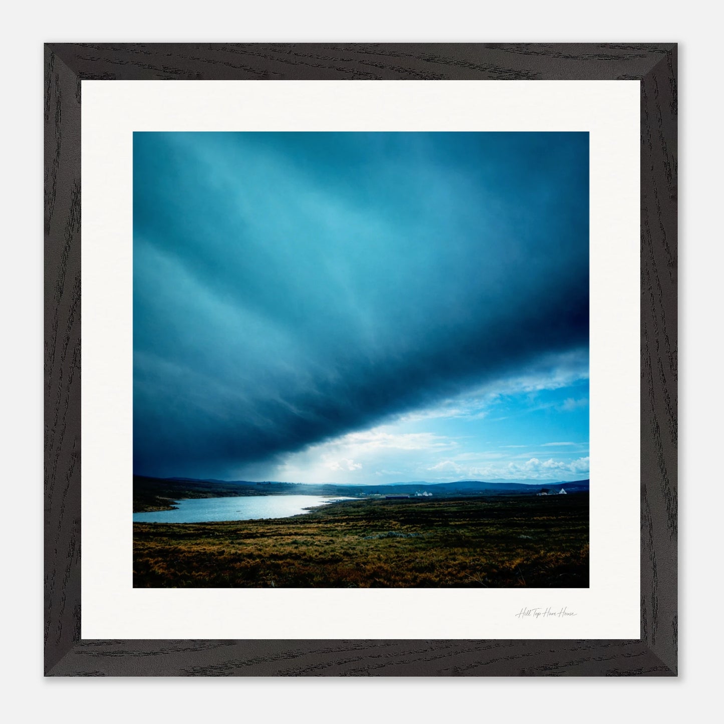 Black Framed artwork of a landscape with a blue sky and body of water.
