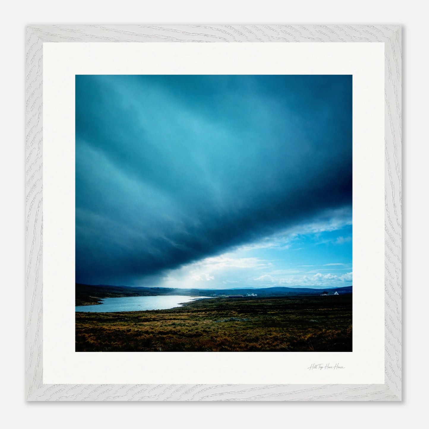 Framed photograph of a landscape with a blue sky and clouds.
