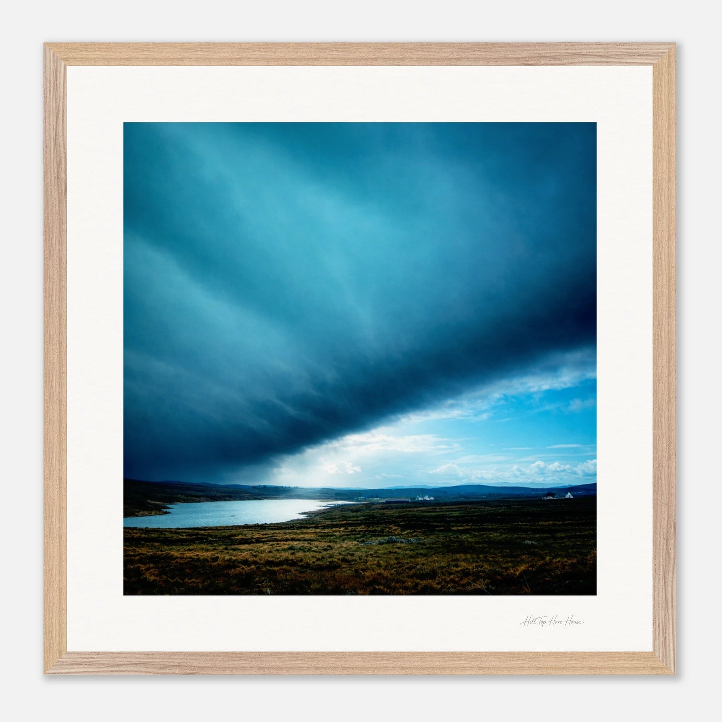 Framed photograph of a landscape with a blue sky and body of water.