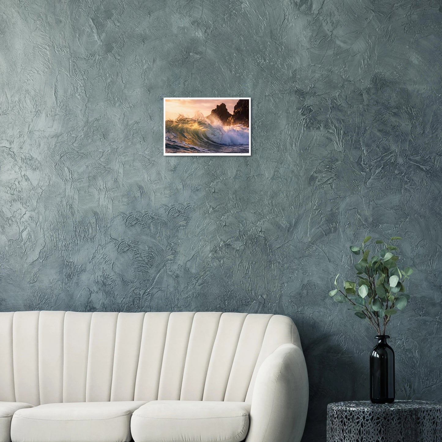 Framed artwork of a sunset over water on a textured gray wall above a white sofa.