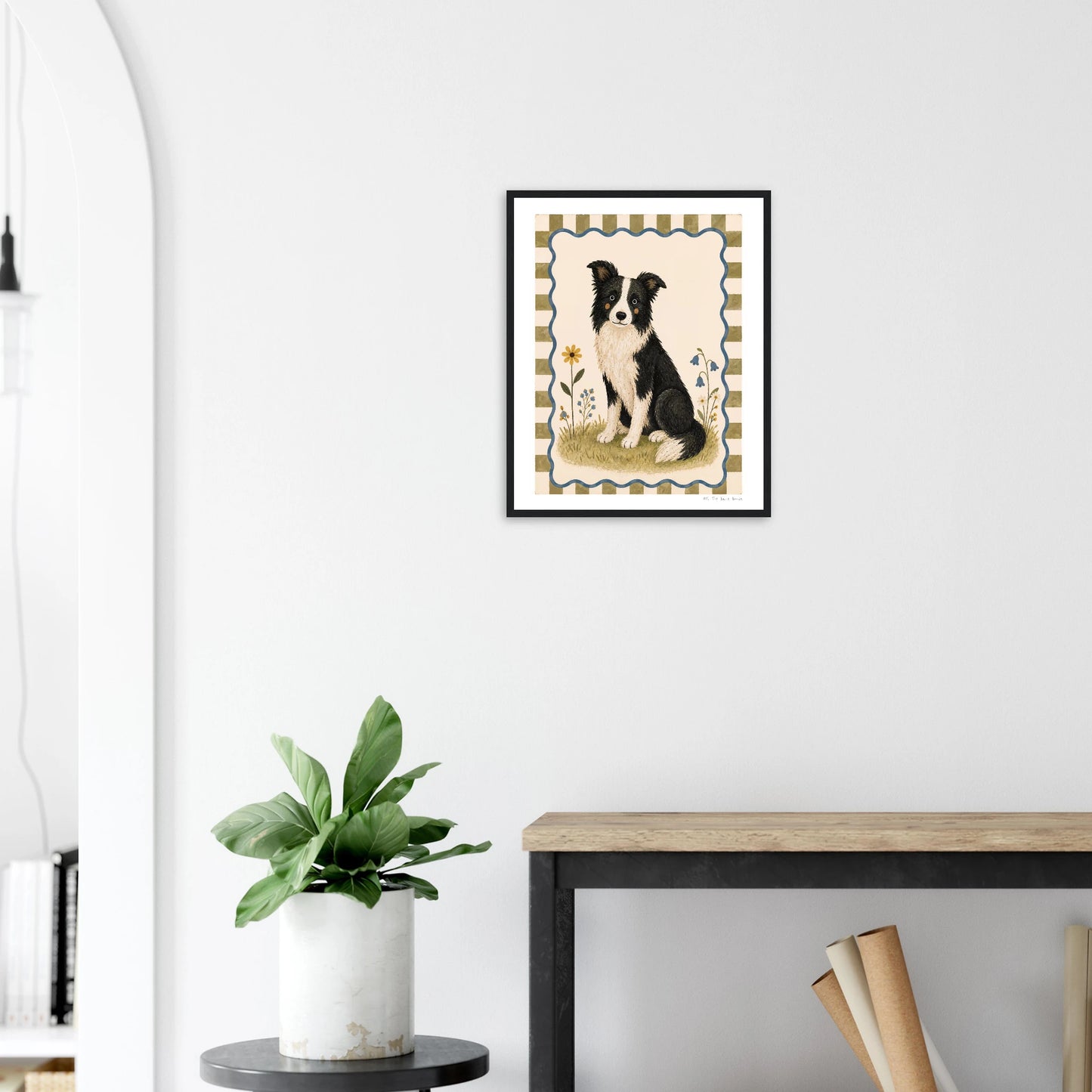Framed artwork of a dog on a wall above a desk with a plant