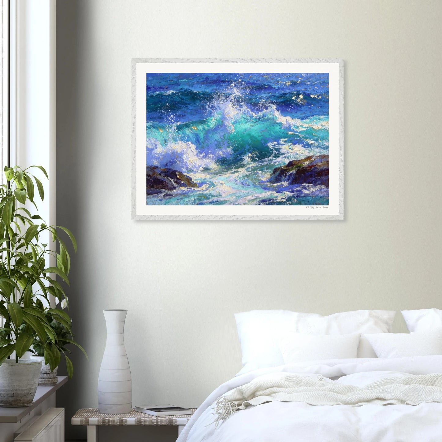 Framed painting of ocean waves on a wall above a bed