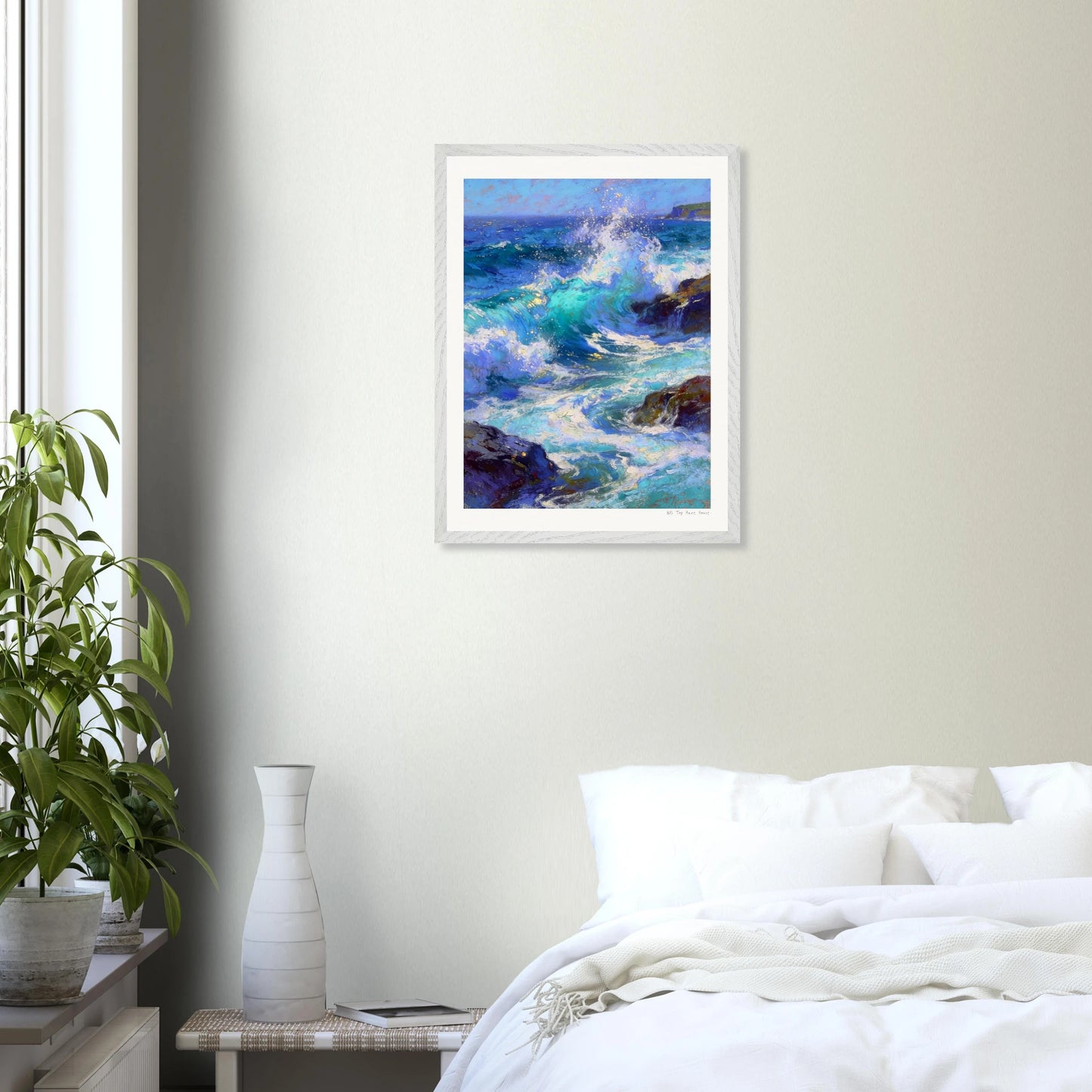 Framed painting of ocean waves on a wall above a bed