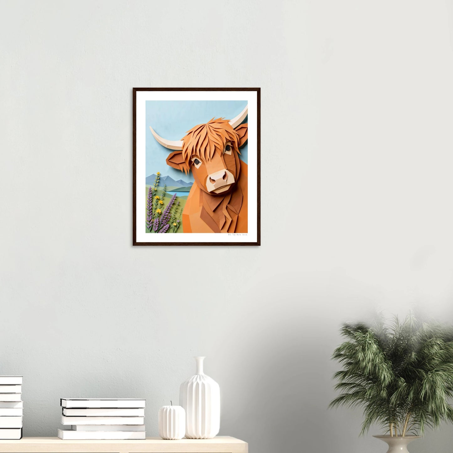 Framed artwork of a brown cow with horns on a white wall.